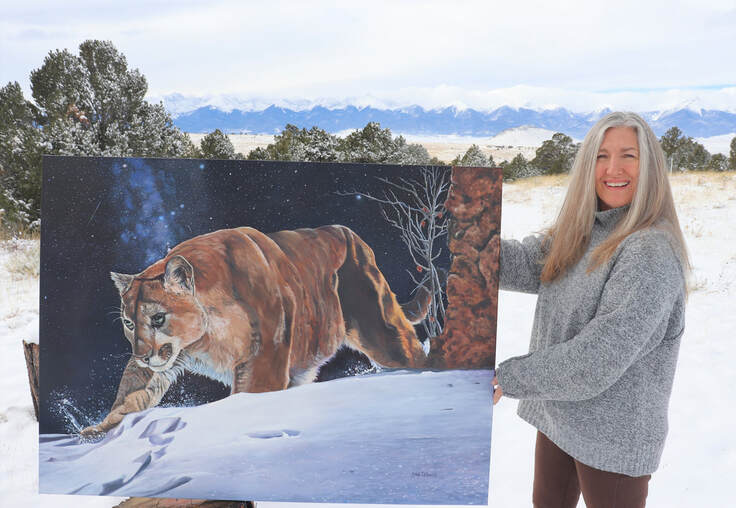 Artist melody DeBenedictis standing with her oil painting of a wild cat